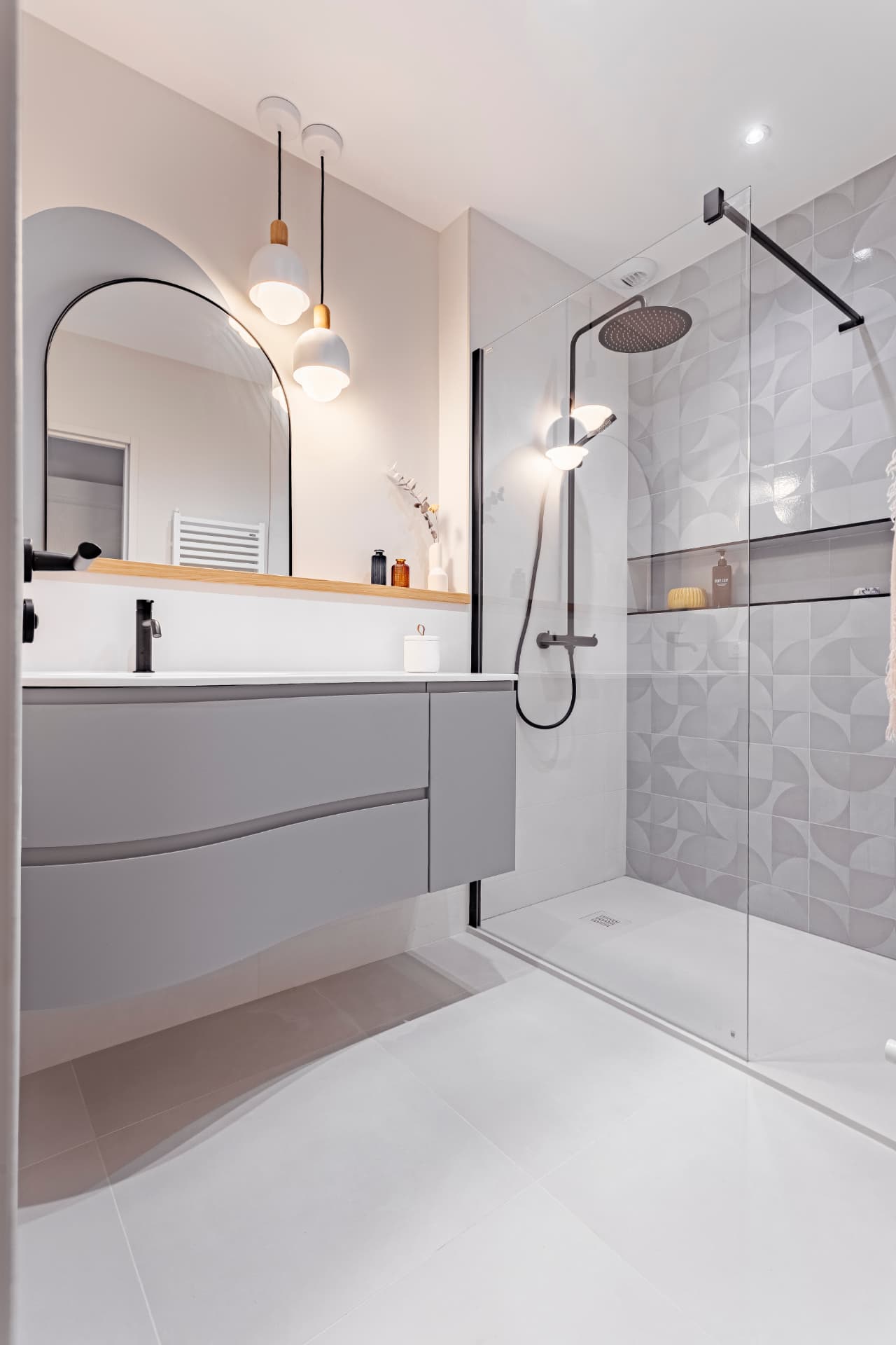 Salle de bain lumineuse : miroir en arche, tablette en chêne massif et suspensions opalines Salle de bain lumineuse : miroir en arche, tablette en chêne massif et suspensions opalines