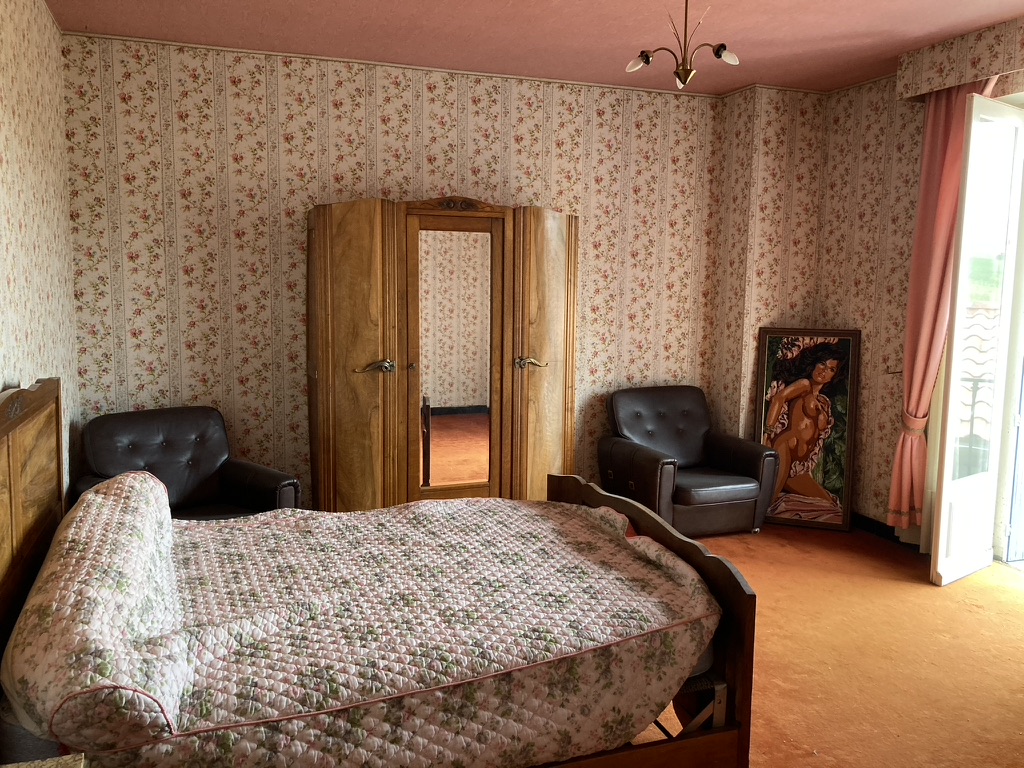 Avant travaux : chambre d'époque avec papier peint fleuri, plafond rose, moquette orange et armoire à miroir — projet à Saint-Gilles-les-Hauts, Ouest de La Réunion