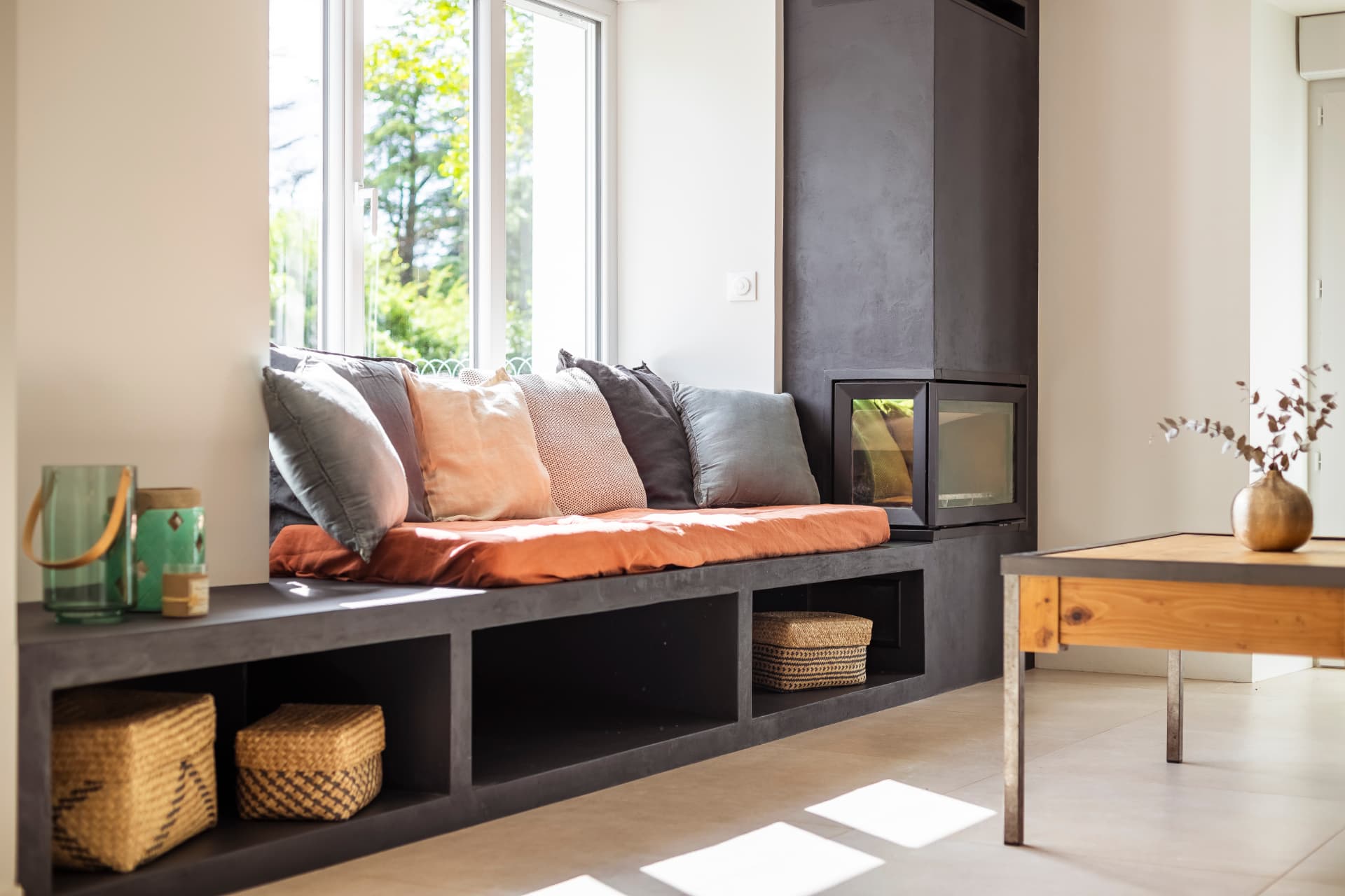 Séjour avec banquette sur mesure en béton ciré intégrant une cheminée