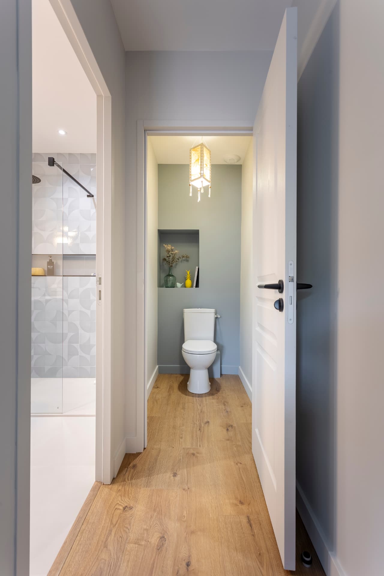 Salle d'eau et WC séparés rénovés : sol imitation chêne, peinture vert d'eau et niche décorative — projet à Saint-Gilles-les-Bains, Ouest de La Réunion