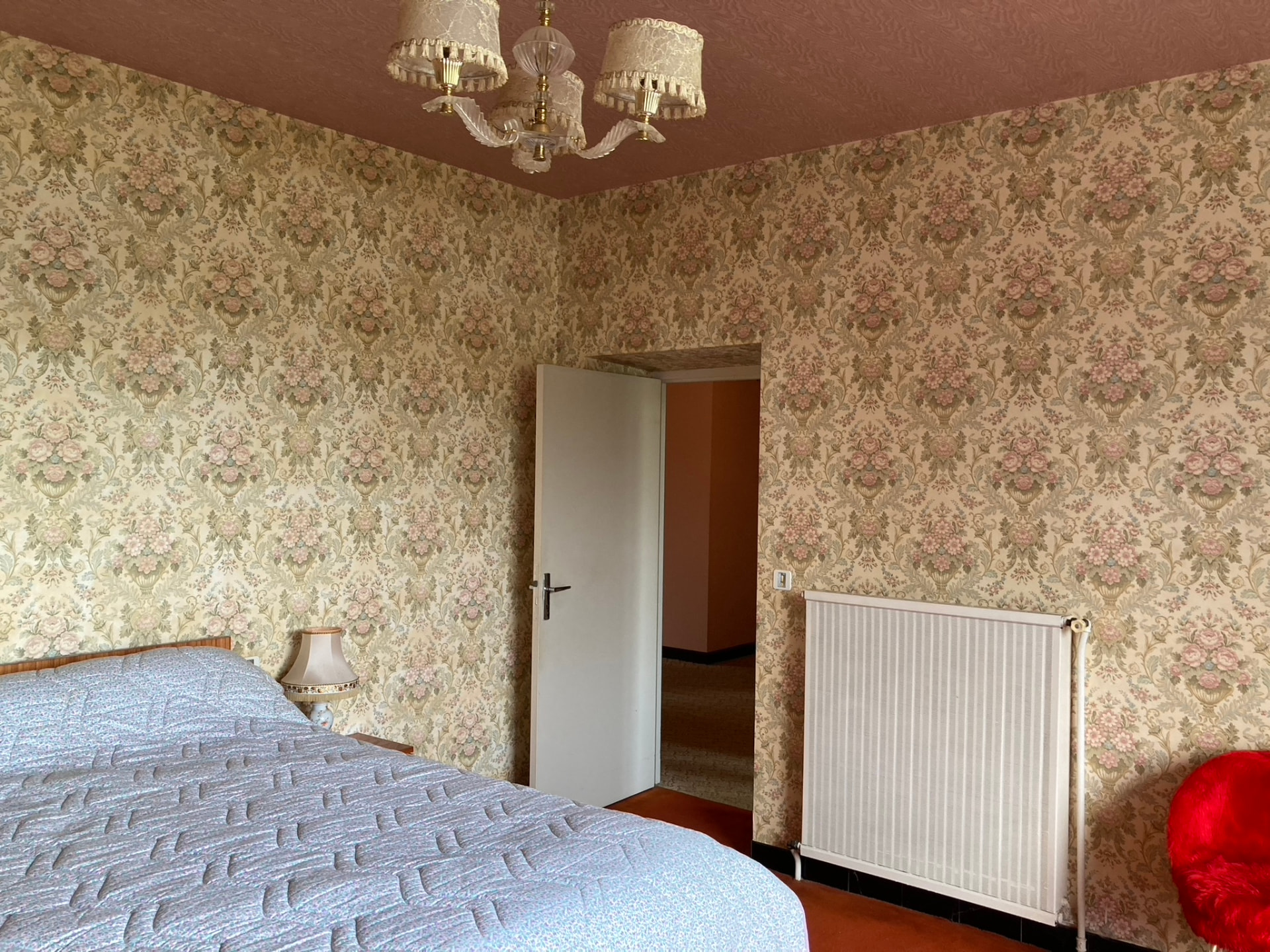 Avant travaux : chambre d'époque avec papier peint fleuri, plafond rose et moquette orange — projet à Saint-Gilles-les-Bains, Ouest de La Réunion