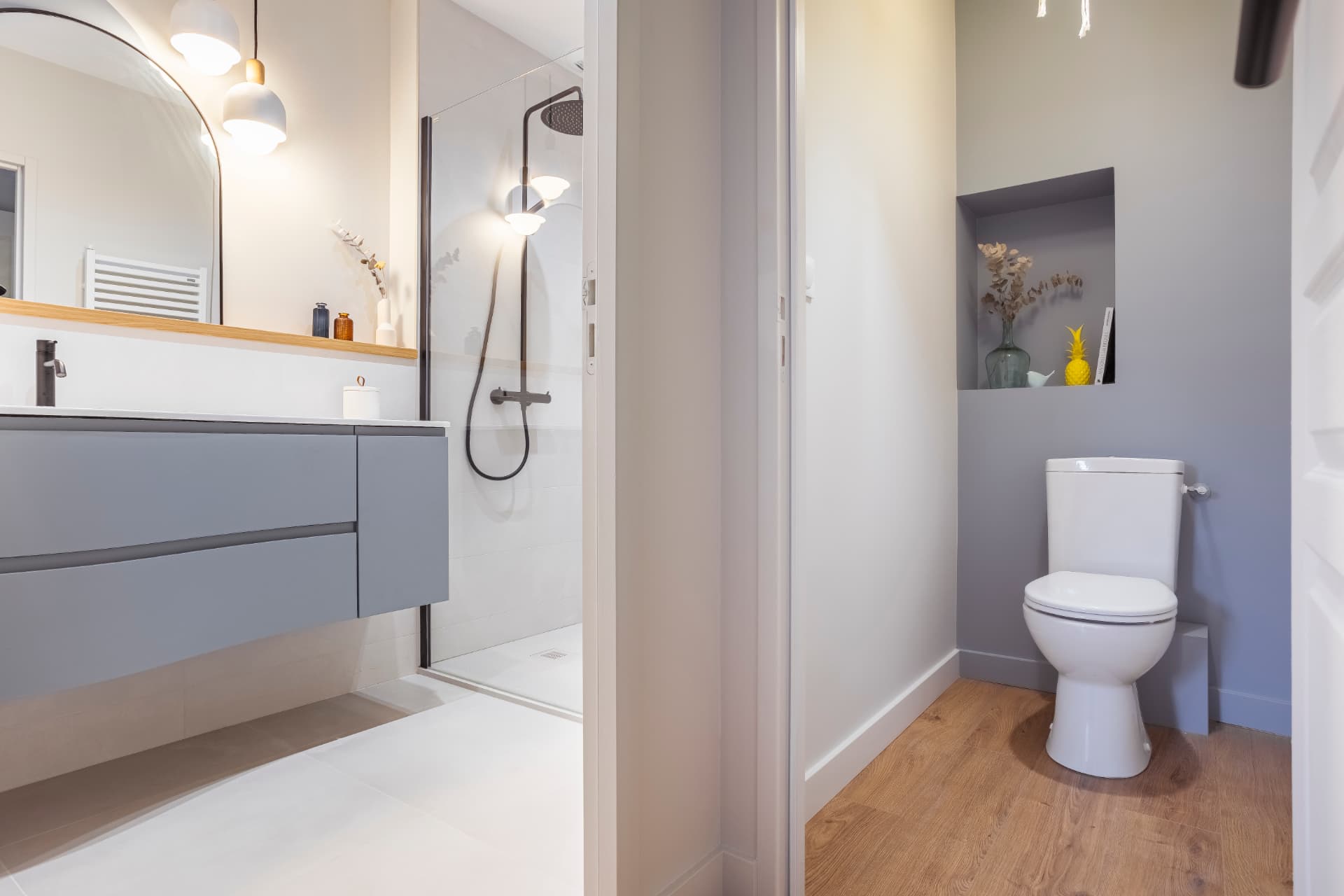 Salle de bain rénovée : meuble suspendu gris, miroir arche et douche à l'italienne — projet à Saint-Gilles-les-Bains, Ouest de La Réunion