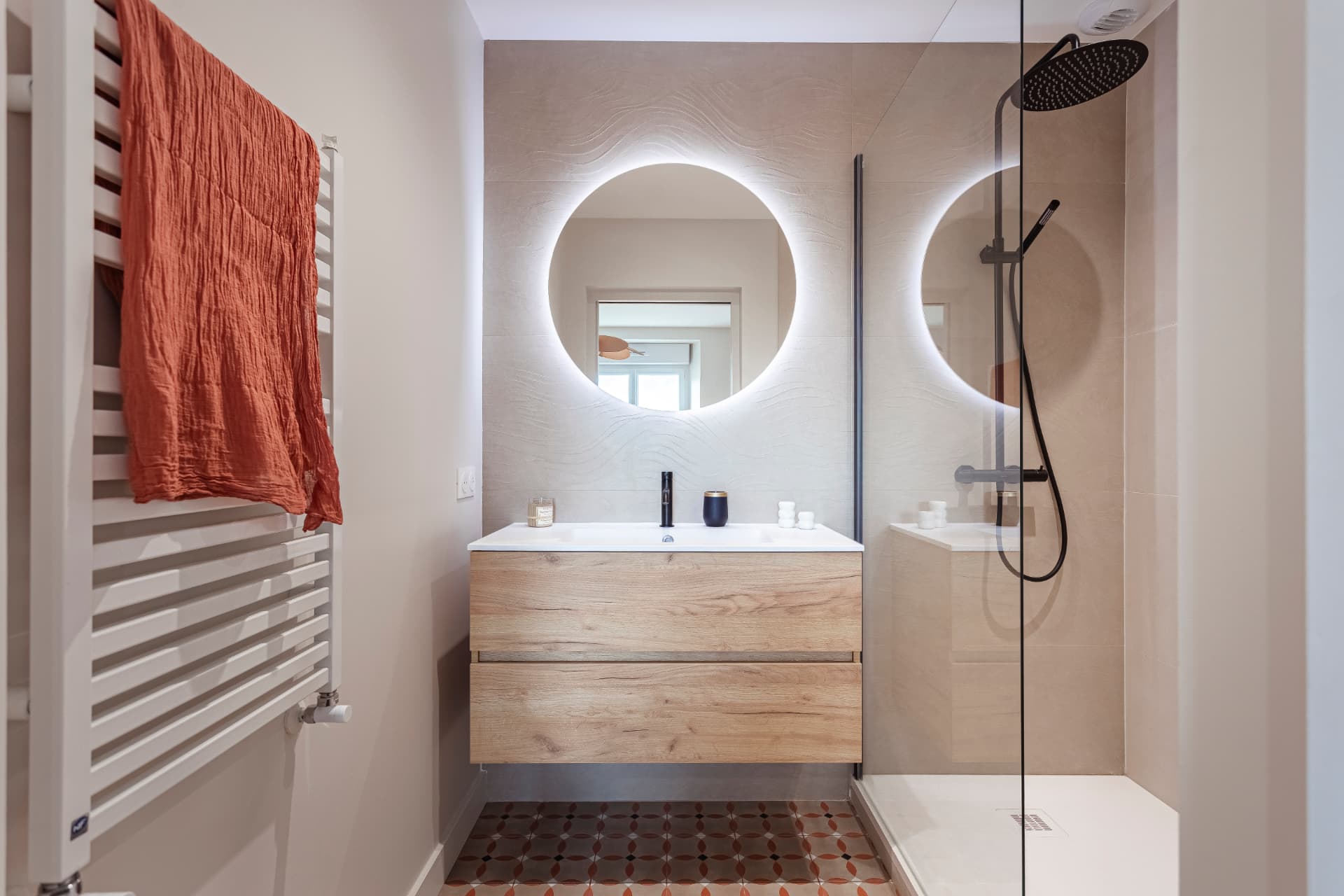 Salle de bain avec carreaux de ciment terracotta, miroir rond rétroéclairé et meuble bois Salle de bain avec carreaux de ciment terracotta, miroir rond rétroéclairé et meuble bois